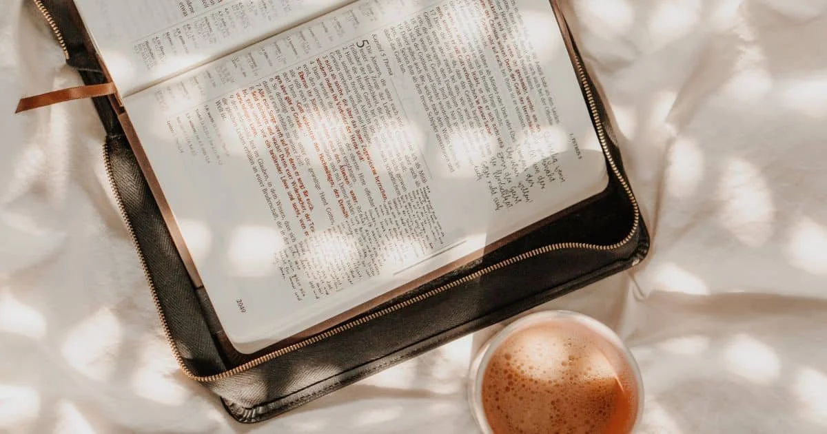 Open Bible with handwritten journal notes and a hot cup of coffee beside the Bible
