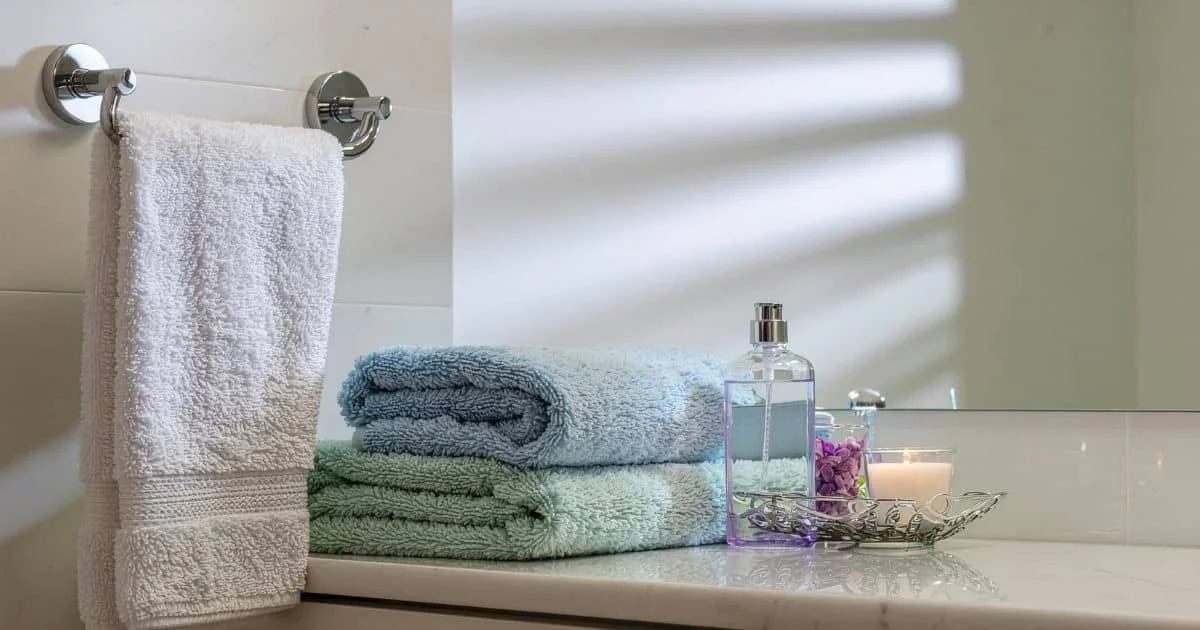 fluffy towels and scented candles sitting on shelf in bathroom