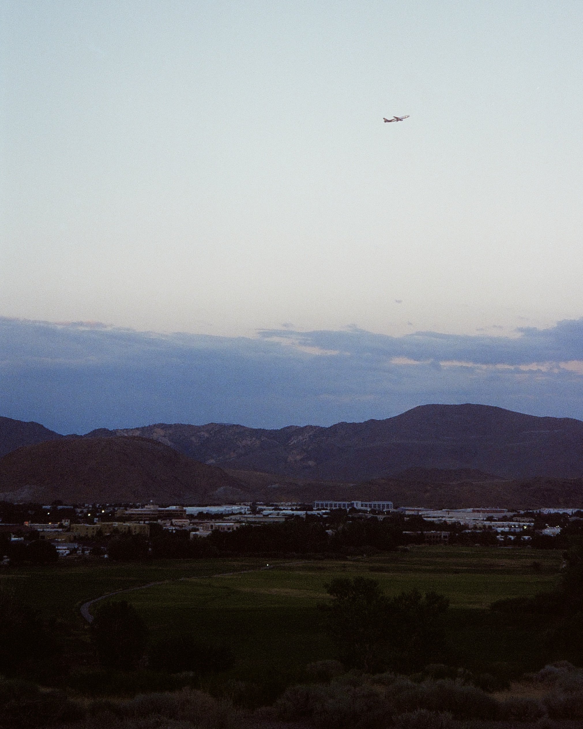 Landscape with mountains, a town, and two airplanes flying in the sky
