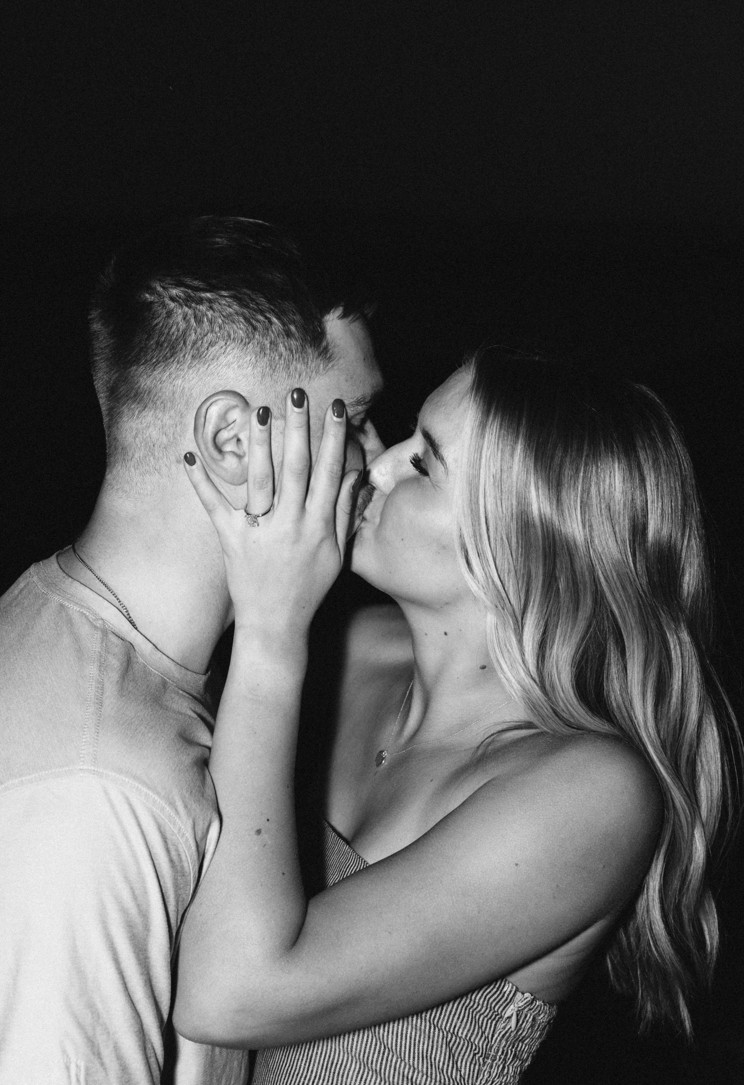 A black and white photo of a couple kissing, with the woman holding the man's face in her hands.