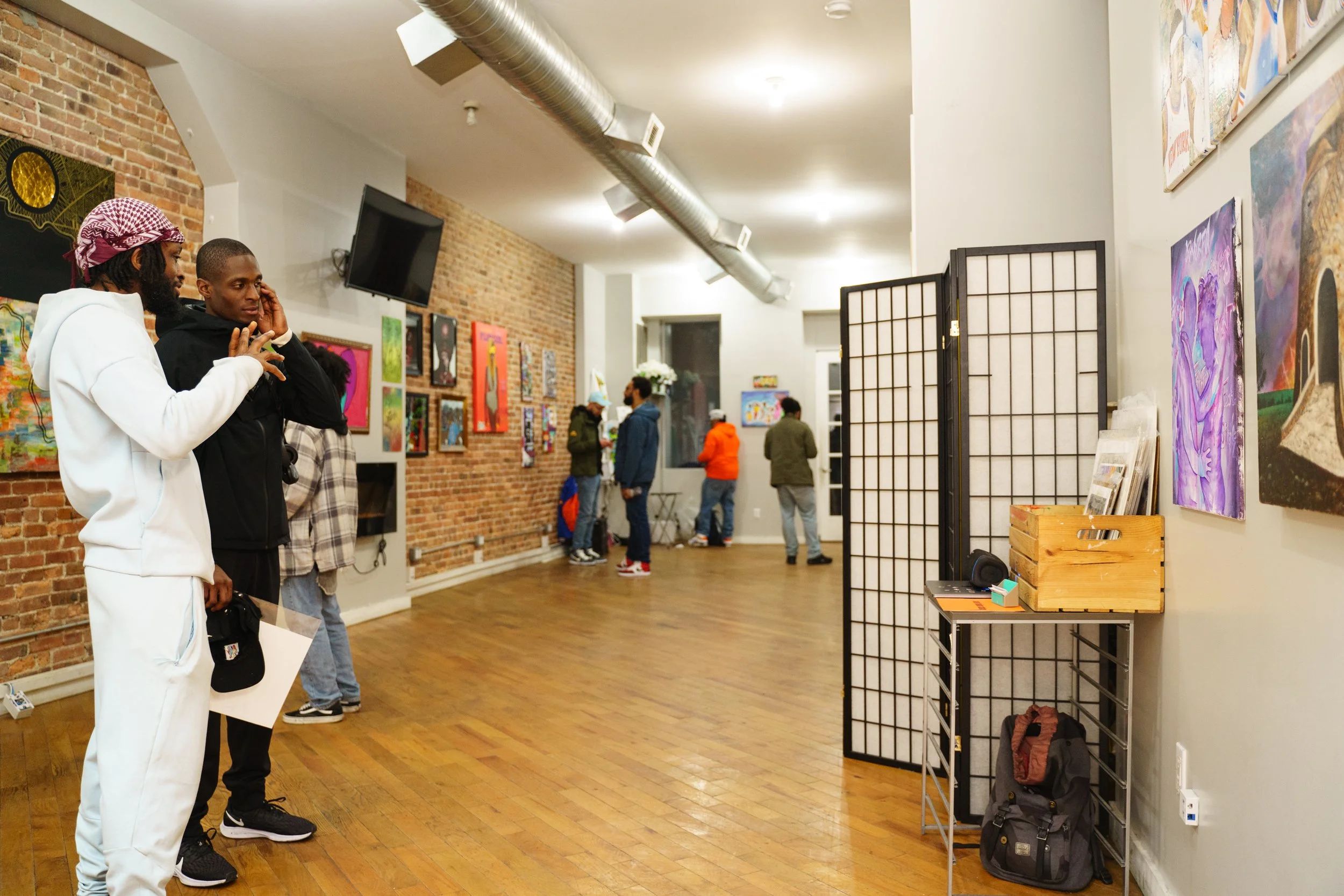  Omari Maynard and Isaiah Frazier talk during an art show organized by Maynard at Hundred Grand Barbershop in Brooklyn, N.Y. on April 10, 2022. The two men, both parents of Little Sun People students, formed a brotherly bond after Maynard’s partner p