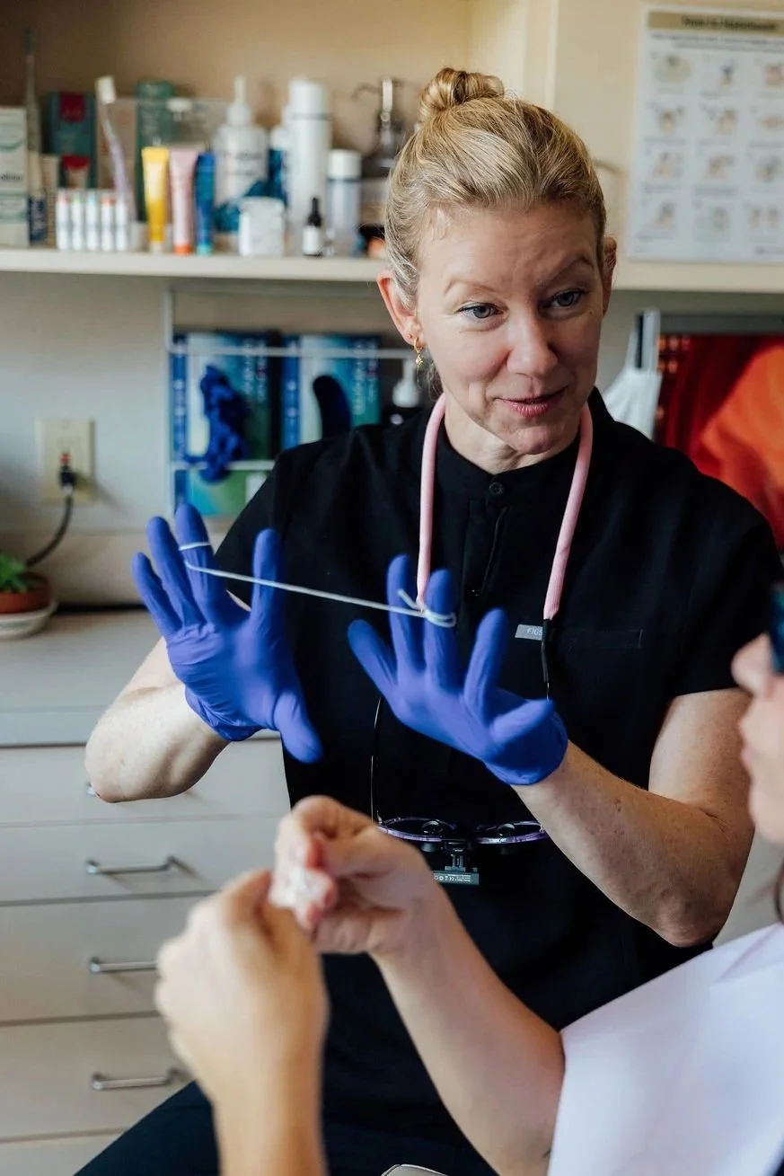 Gina, our incredible hygienist, demonstrating proper flossing technique to a patient.