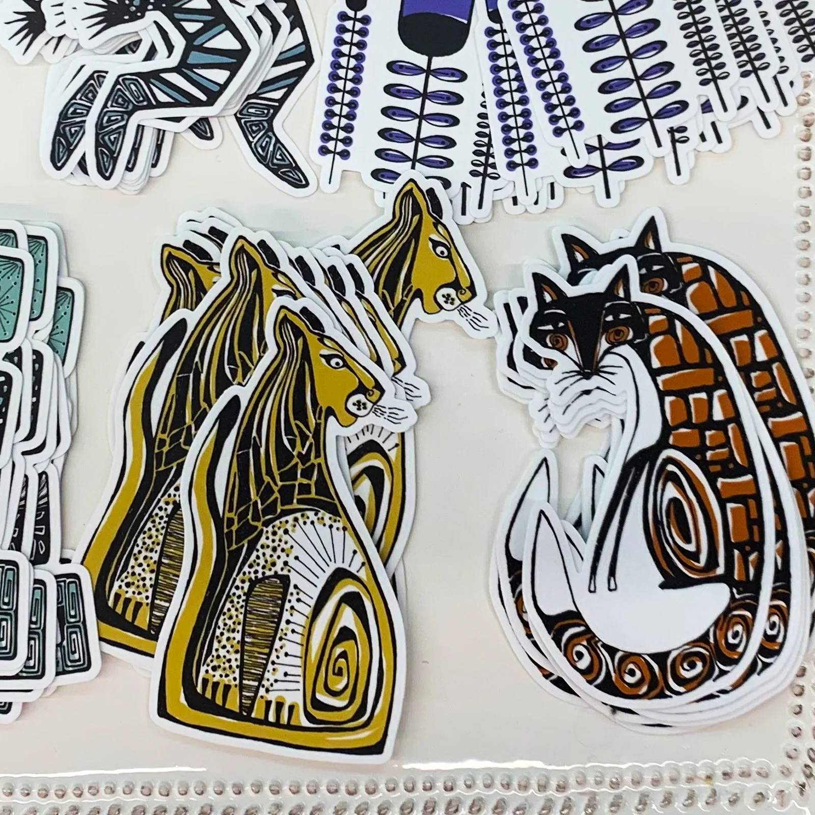 Sticker sheet featuring stylized illustrations of animals including two lions and a fox, with other floral and geometric designs.