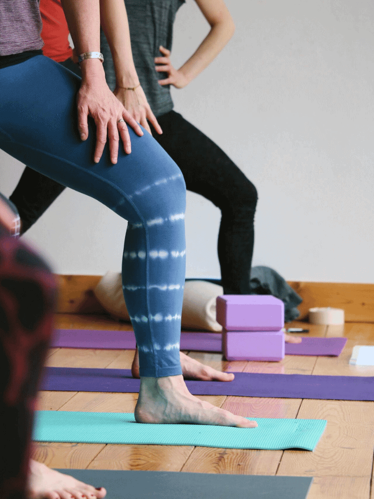 People practicing yoga or stretching on yoga mats with blocks and props in a room.