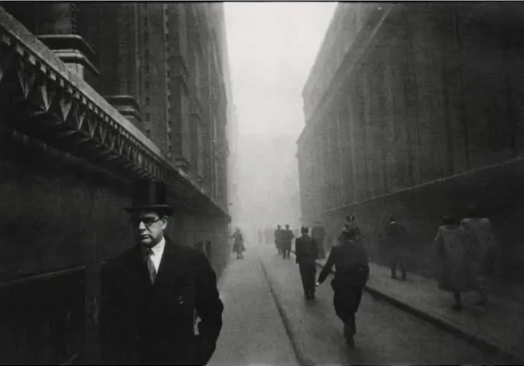 old black ad white photo of a man with a black hat surrounded by people walking