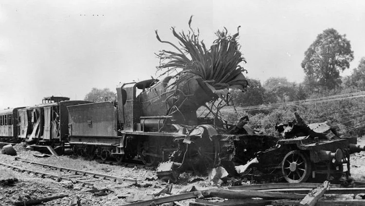 black and white old photo of a car crashed into a train
