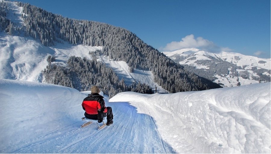 man on a sleight in the snow with mountains around