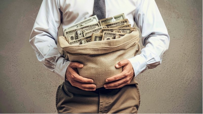 businessman in a suit holding a big sack with US dollar bills