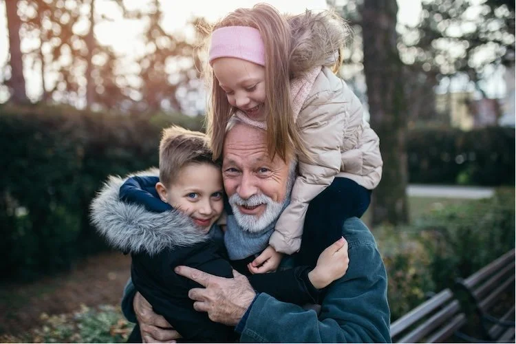 grandfather playing outdoors with granddaughter and grandson