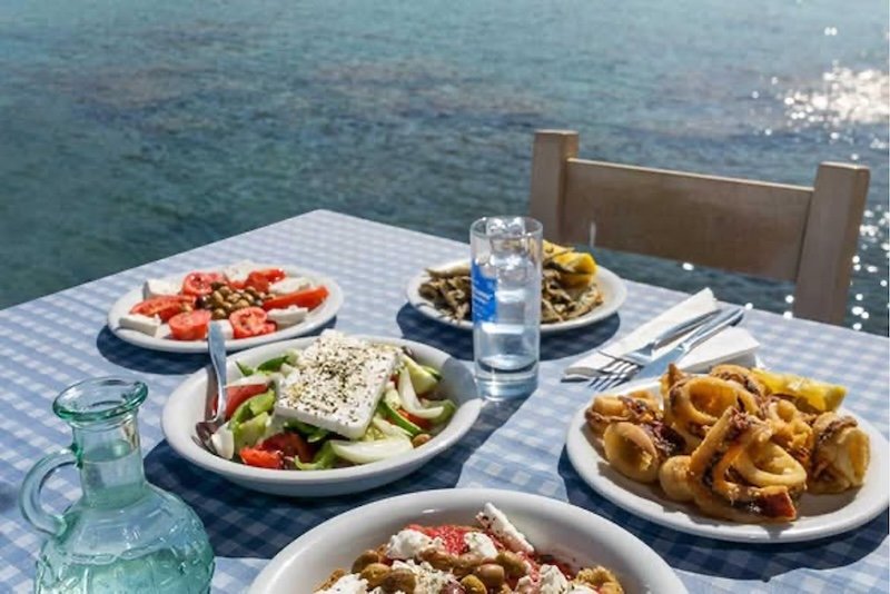 a Greek taverna lunch by the sea with plates full of food