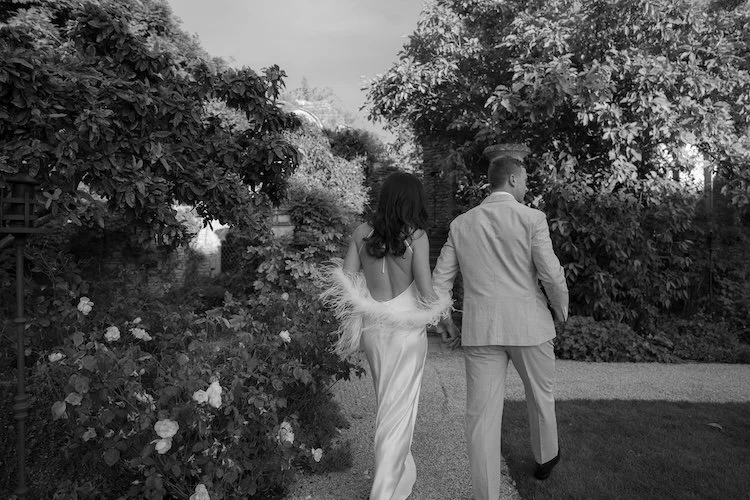 A bride and groom walking through the English Country Garden at Euridge