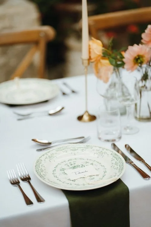 Rehearsal dinner table set up with vintage style floral plates and candle sticks
