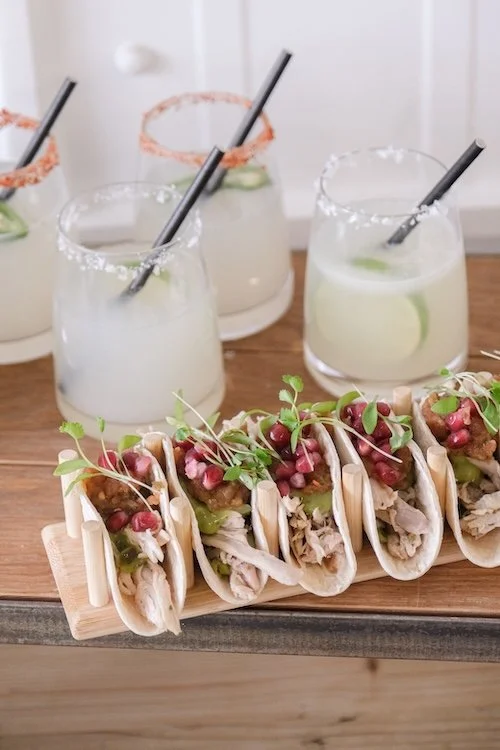 A wooden tray of tacos with spicy and normal margaritas