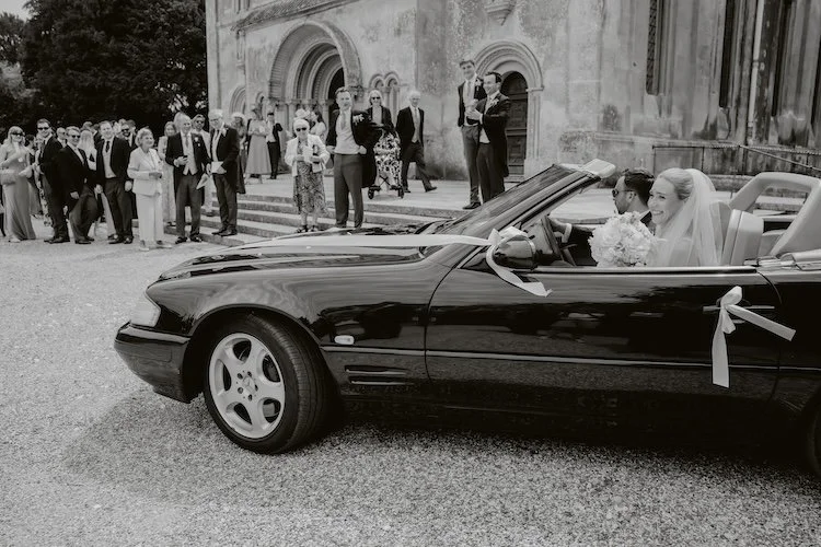 Couple leaving their wedding ceremony in a vintage car