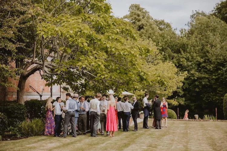colourful wedding guests stood in an english garden