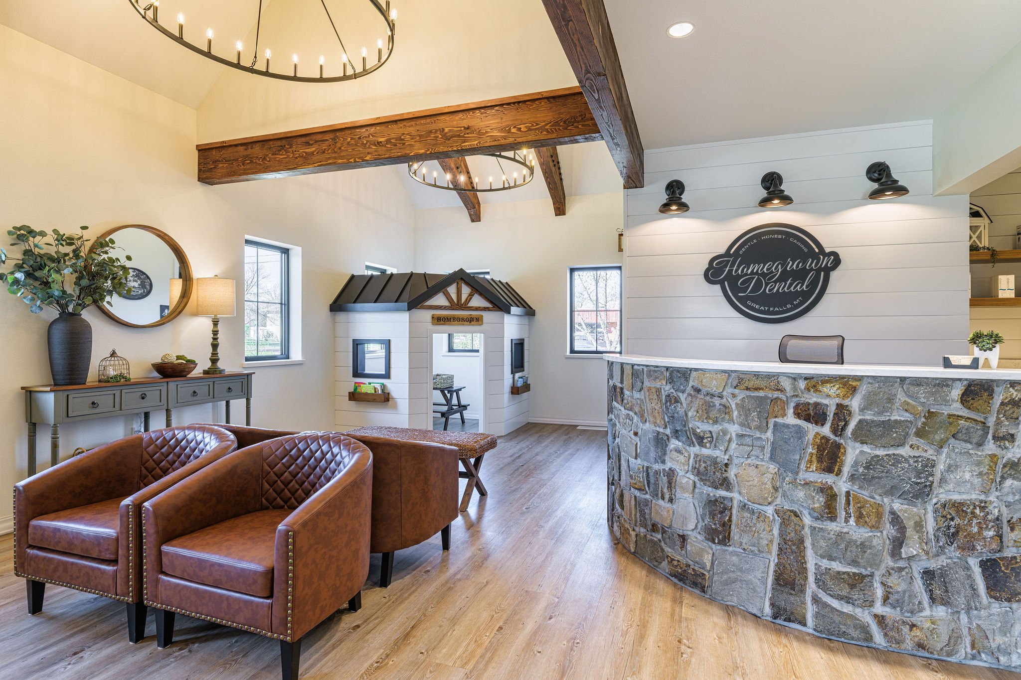 Homegrown Dental interior photos! The waiting area is designed as a living room setting with warm tones of wood from the stained glulam trusses and its feature fireplace in natural stone veneer. The dental practice is equipped with its own lab, steri