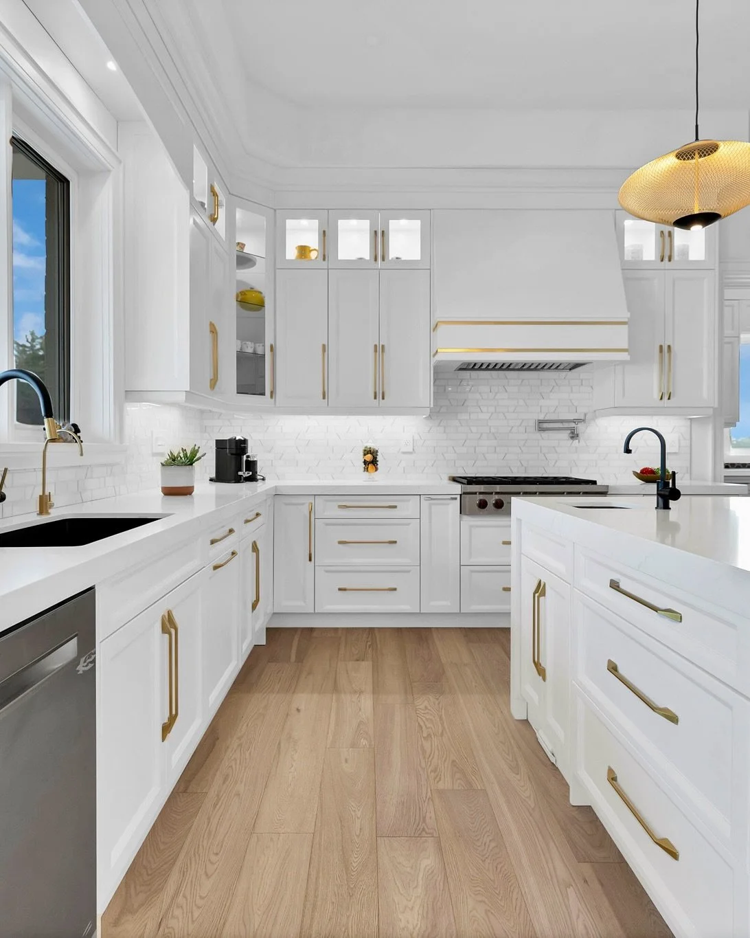 Inside Project Georgetown, this transitional kitchen is designed around a clean white palette, complemented by bold gold accents and neutral white oak engineered hardwood flooring.

Large windows bring in an abundance of natural light, reinforcing th