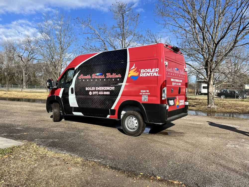 Red service van with logo for South Texas Boiler Industries parked in an outdoor area with trees and grass.