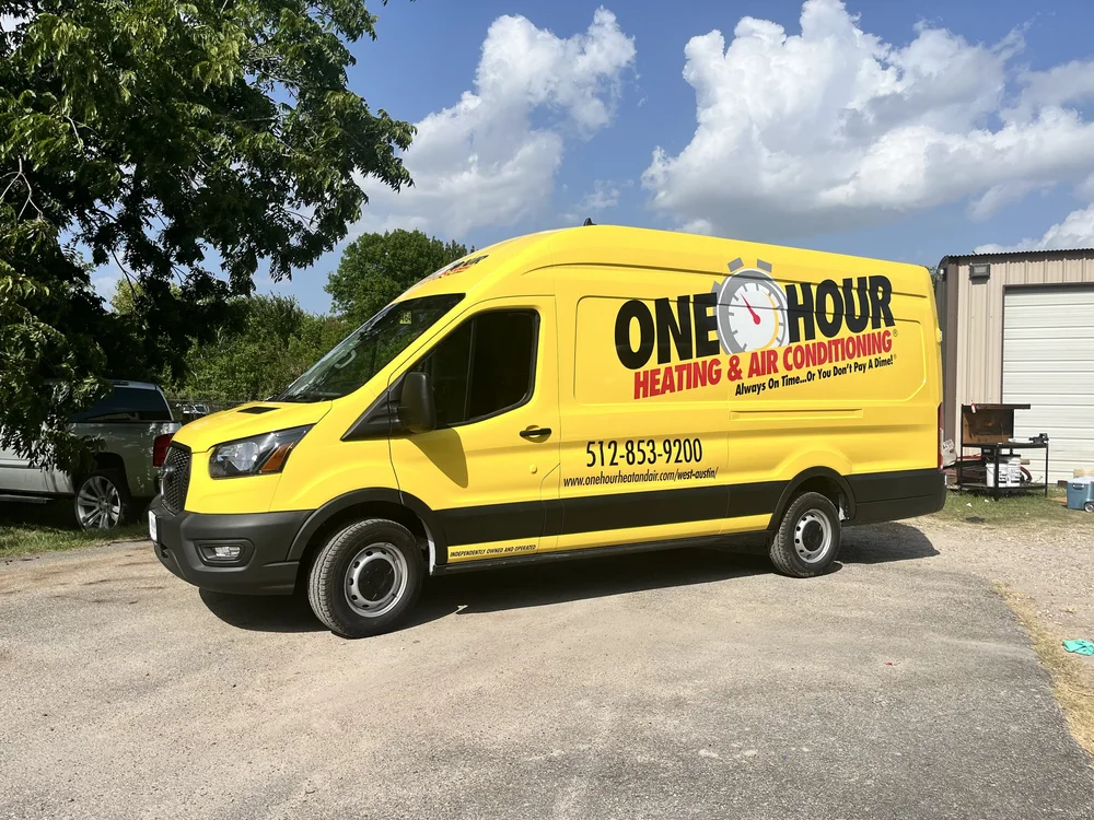 Yellow van for One Hour Heating & Air Conditioning with company logo and contact information, parked outdoors.
