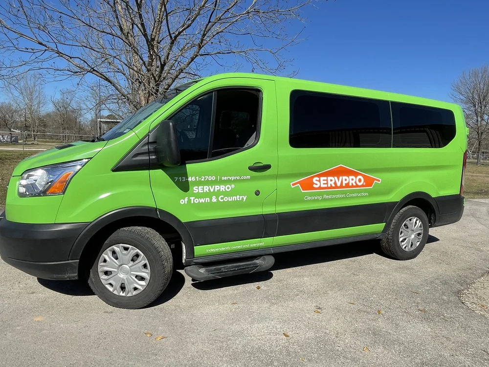 Green SERVPRO van parked outdoors, featuring company logo and contact information.