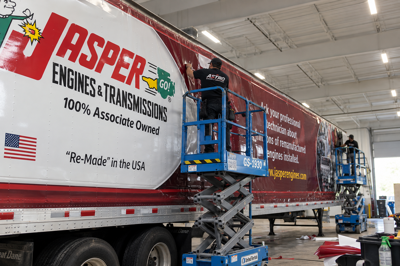 Installation of Jasper Engines and Transmissions graphics on a commercial trailer, with Astro installers working from lifts
