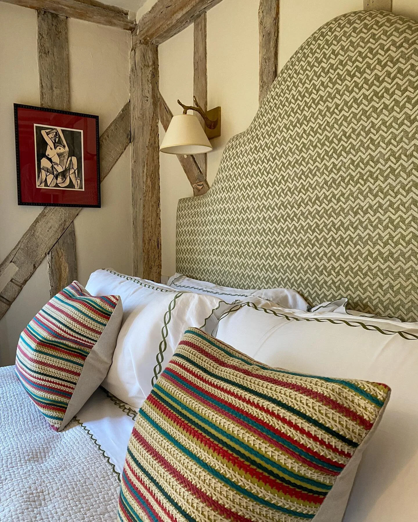 Fresh bedroom scene enhanced by a bespoke headboard in Chiltern fabric by @fermoie; Twig down light from @vaughandesigns; embroidered sheets and a Picasso print.