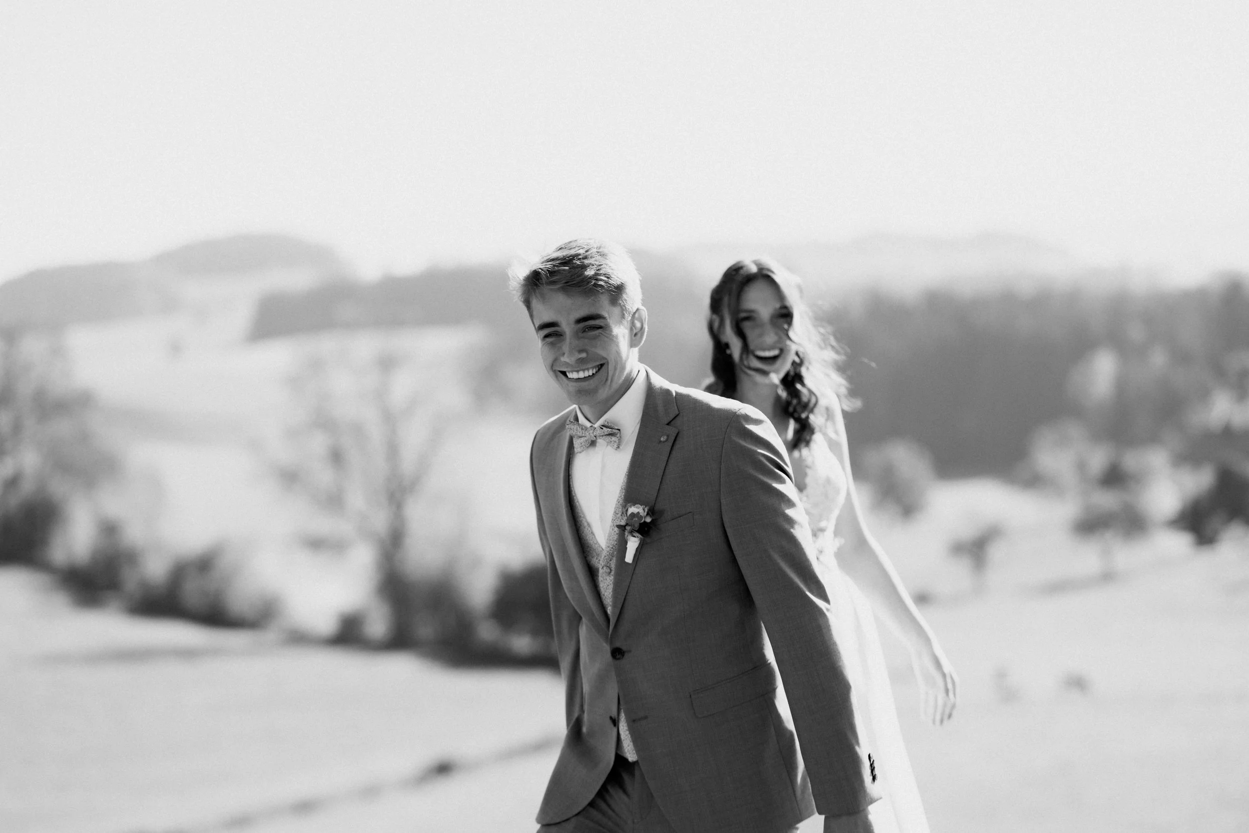 Ein lachendes Brautpaar im Freien, schwarz-weiß Foto, glückliches Moment bei einer Hochzeit