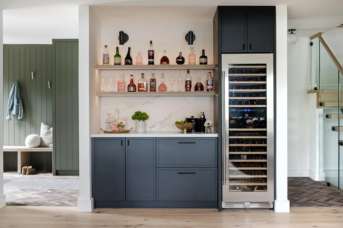 What&rsquo;s not to love about this family room bar (and that sweet foyer and staircase in the background:) 
⁠
From the full-height wine fridge to the dark, moody cabinetry and dramatic slab backsplash, this bar checks every box for style and functio