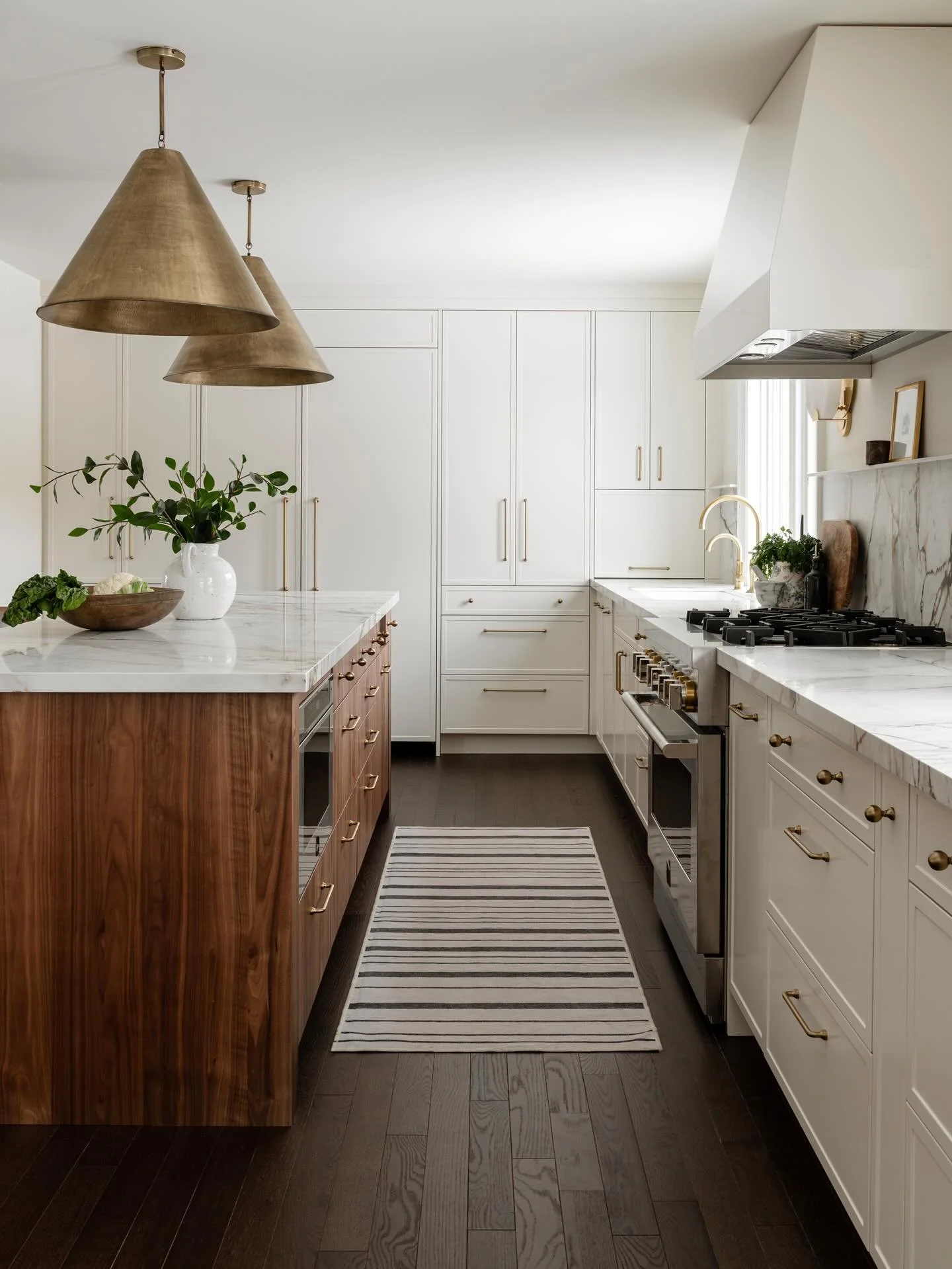 This kitchen went from dated to dreamy with a warm, modern refresh. Rich walnut tones bring depth and warmth, while gorgeous porcelain countertops brighten the space with a clean, timeless feel. Finished with brushed gold pendants for just the right 