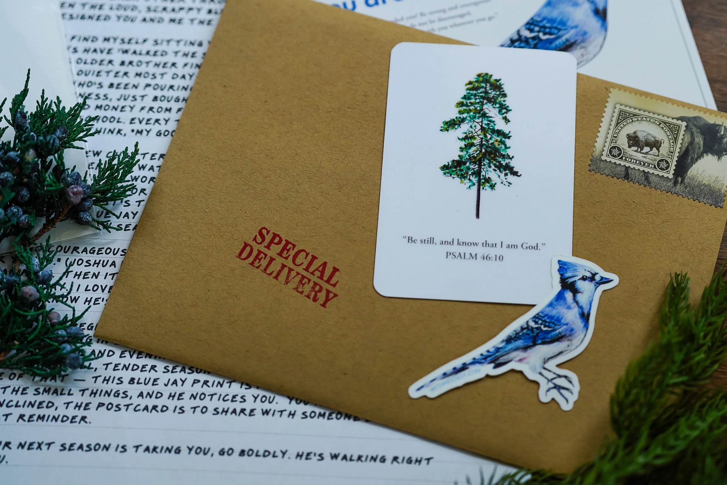 The OUT Post snail mail subscription flat lay featuring watercolor nature art print, encouraging faith letter, and pass-along postcard for Christian women who love the outdoors