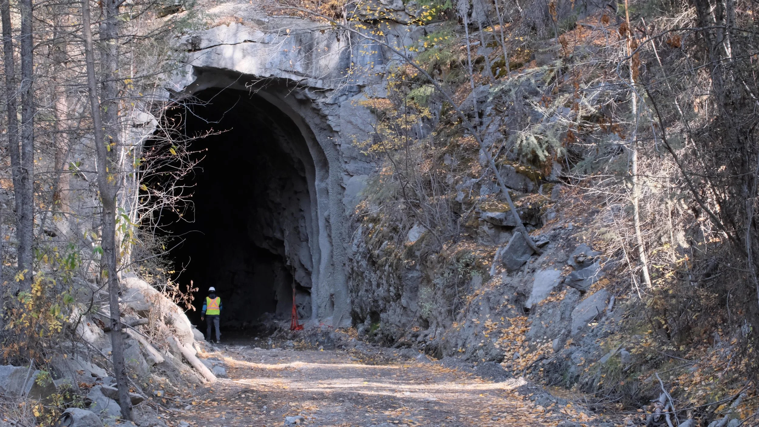 The southern entrance of the Adra Tunnel along the Kettle Valley Rail (KVR) Trail above Naramata. Dean Douglas walking into the tunnel to shocase the height comparison of the tunnel compared to a human.