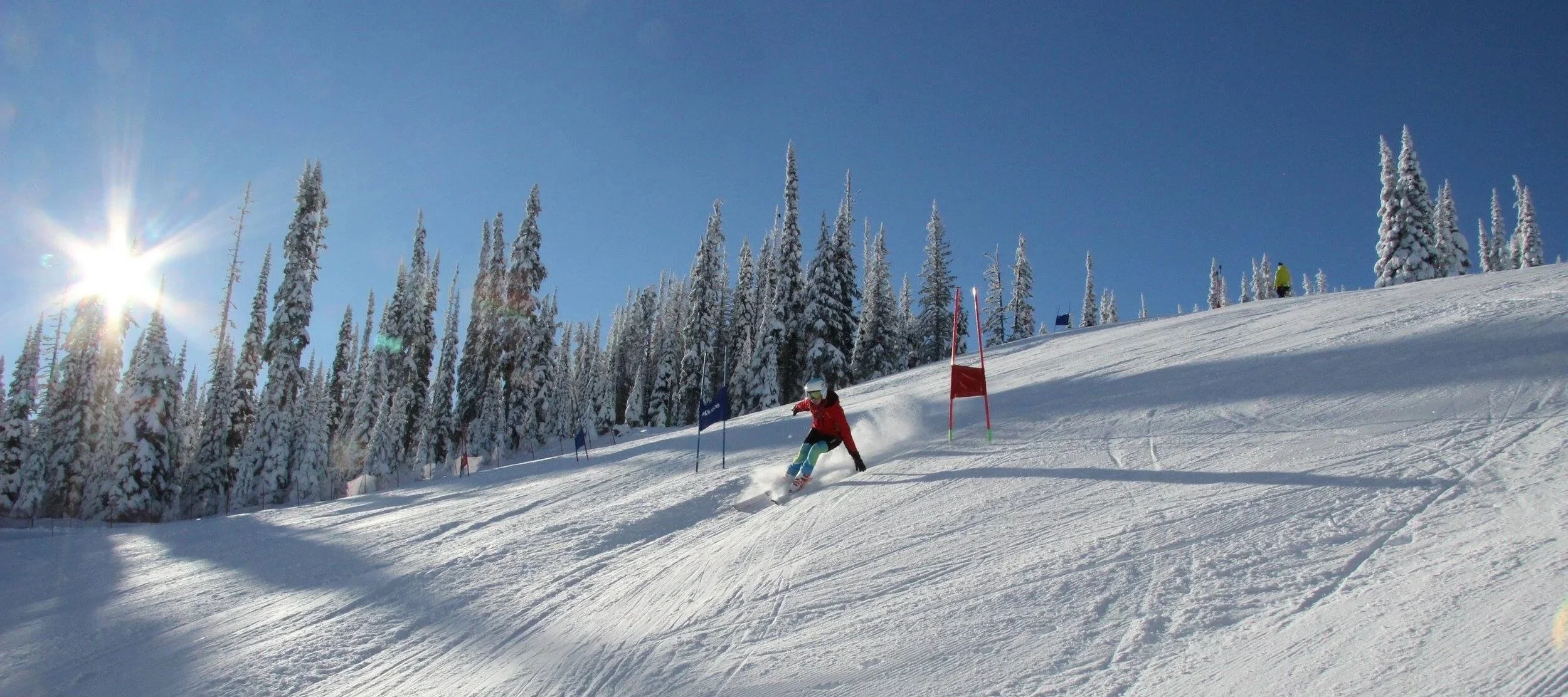 Ski racer training through gates at Sun Peaks BC ski camp with fresh snow and mountain views