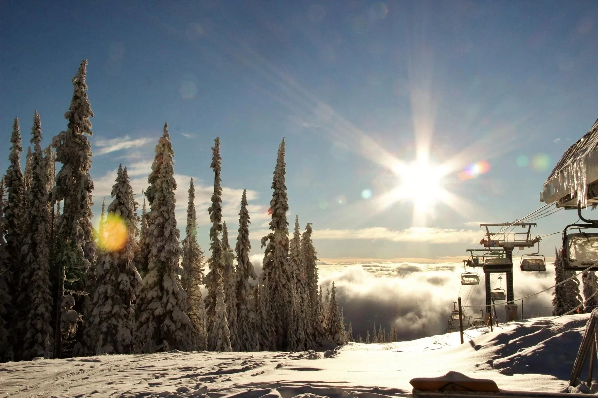 Scenic sunrise above clouds at Sun Peaks ski resort with chairlift and snow-covered alpine terrain