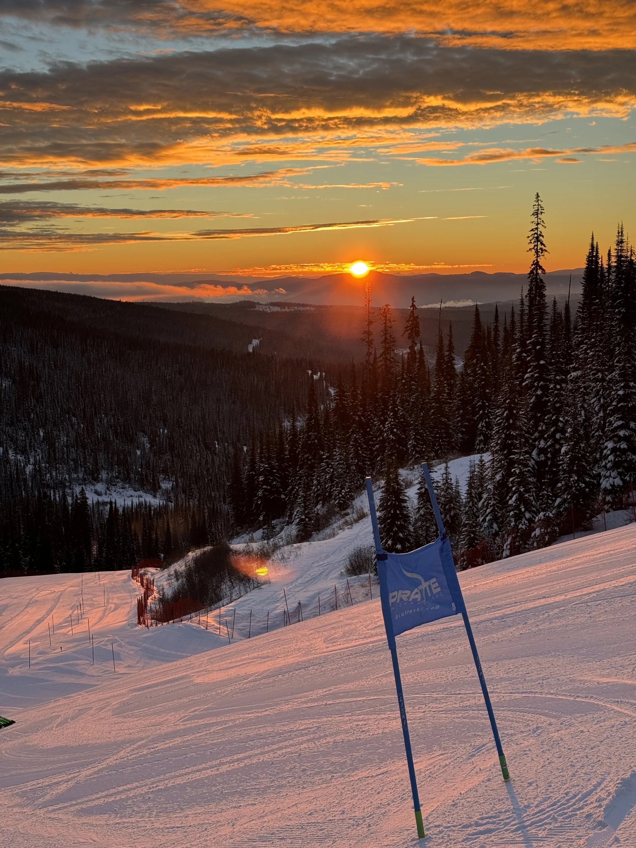 Golden sunset over race course at Sun Peaks BC with alpine ski training gates and mountain scenery