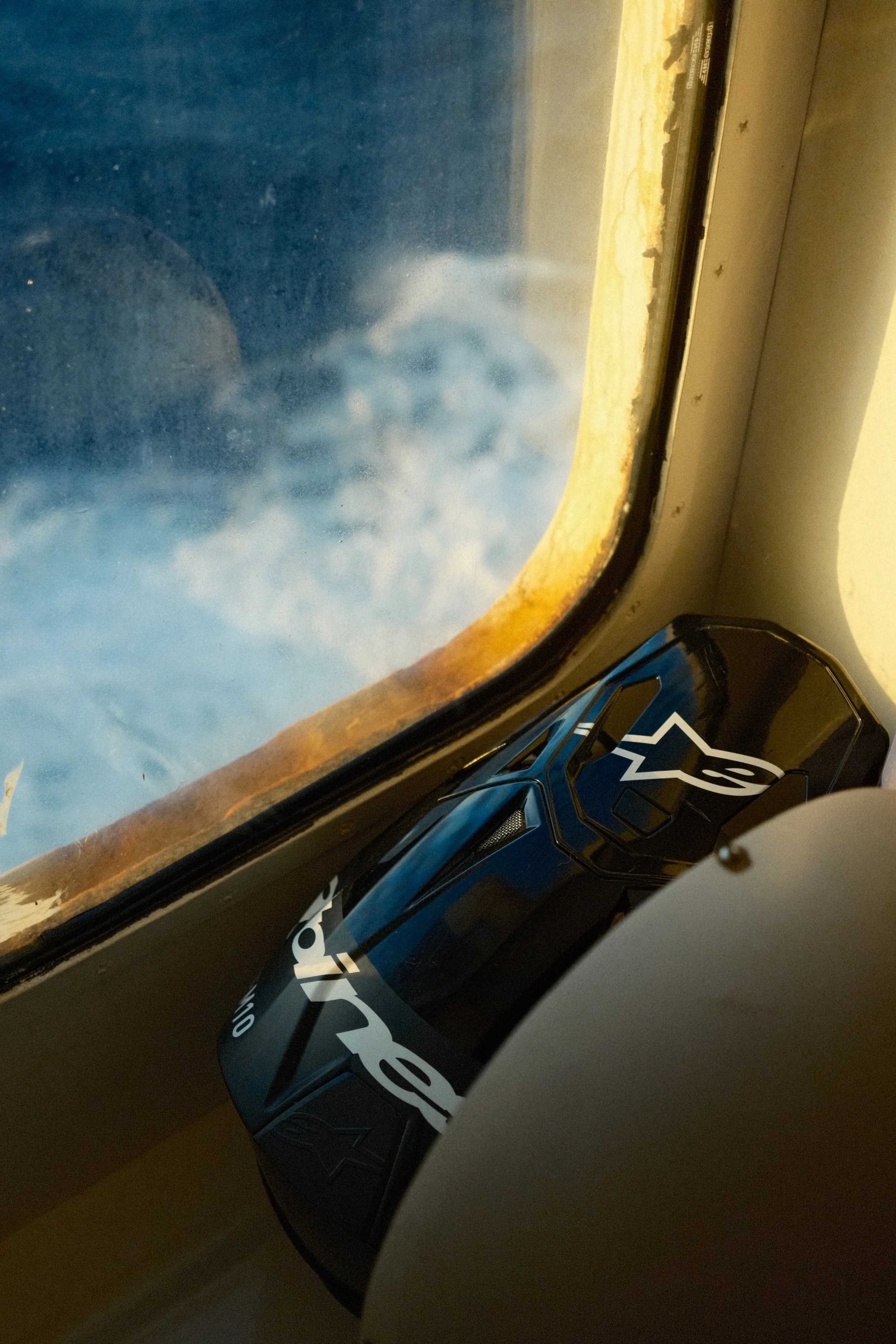 Une capsule de café noir avec un logo blanc, posée sur un rebord sous une fenêtre, avec un paysage urbain visible à l'extérieur.