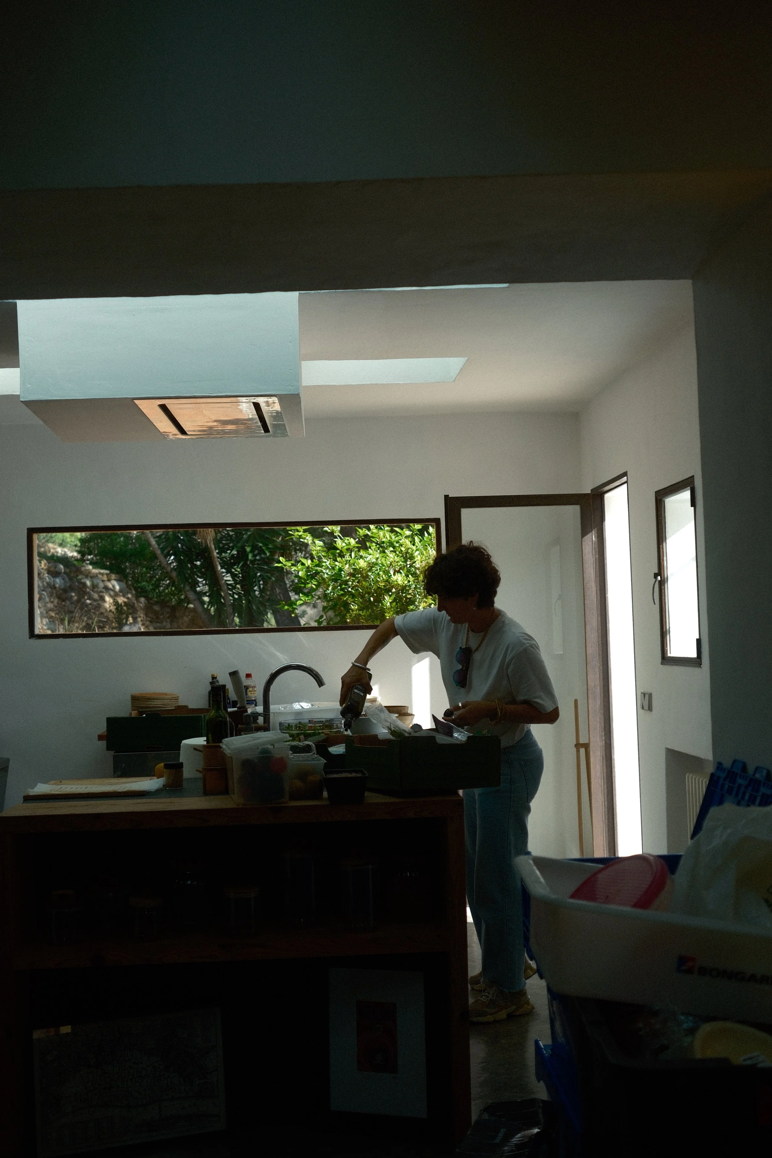 Personne en cuisine près d'une fenêtre ouverte, préparant des aliments.