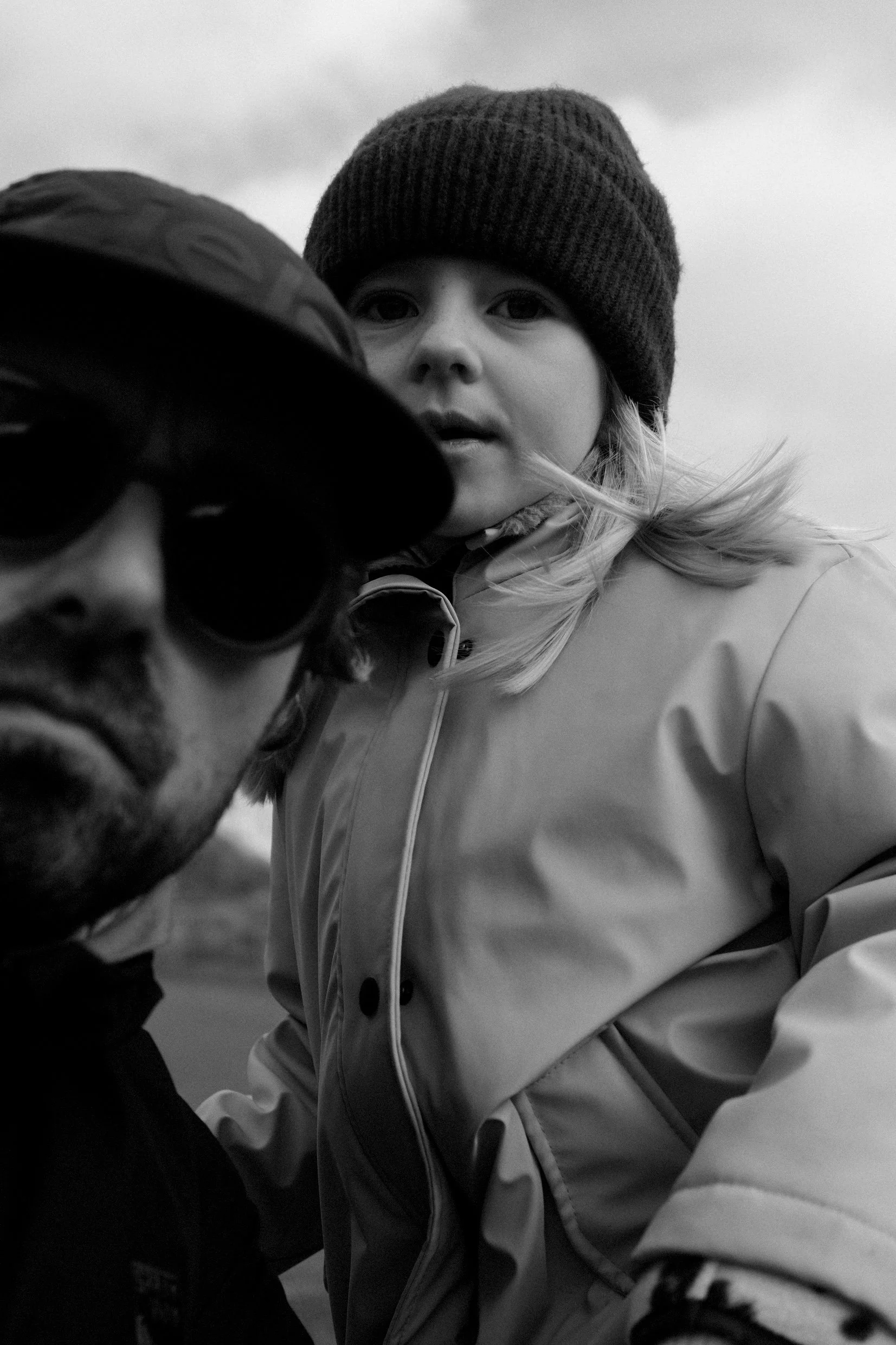 Une femme et un homme prennent une selfie, l'homme porte des lunettes de soleil et une casquette, la femme porte un bonnet et une veste.