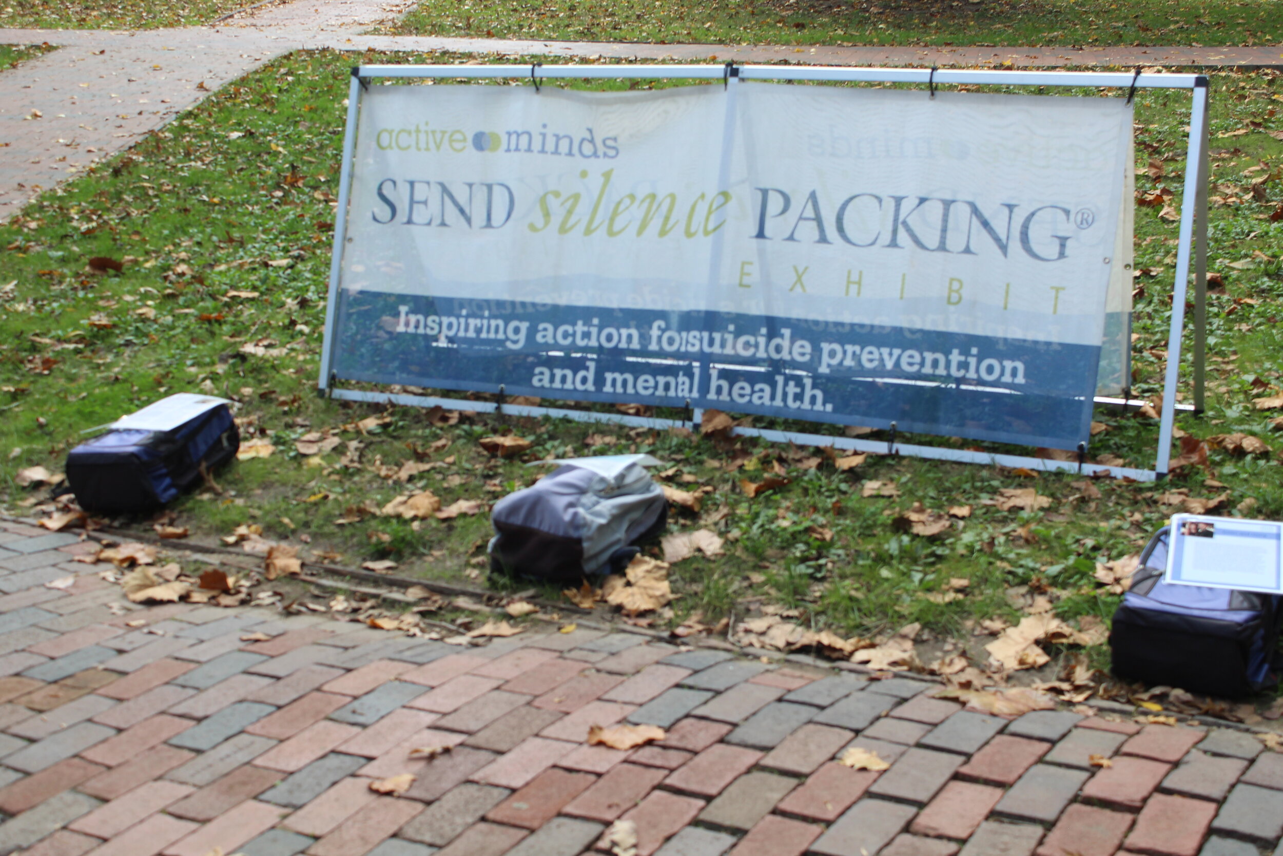  “Send Silence Packing” banner lays behind some of the bookbags for the exhibit. Photo by Emily Zeiler. 