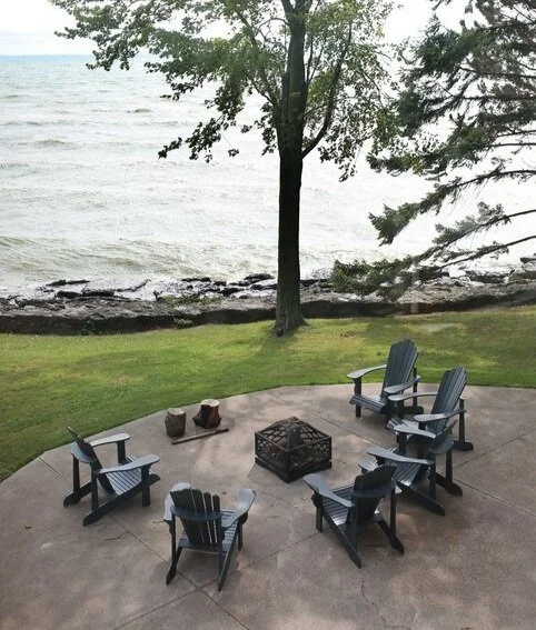 Muskoka chairs around a fire pit with a view of the lake