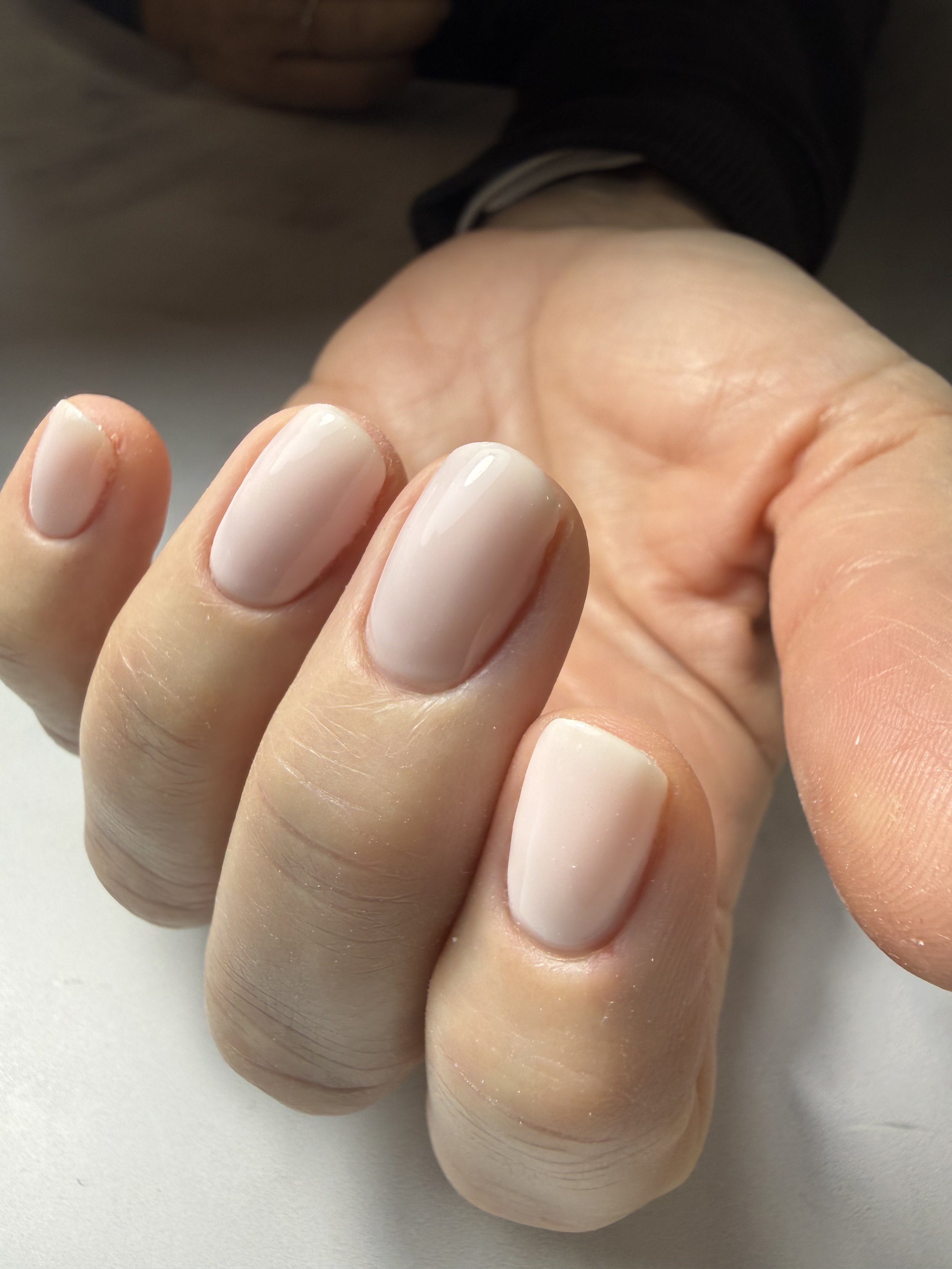 Close-up of fingers with neatly manicured nails painted in a light nude color.