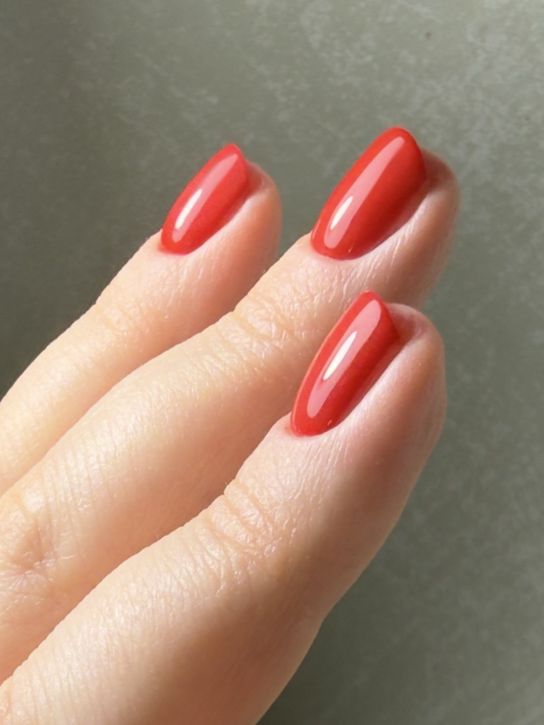 Close-up of a hand with nails painted in bright red, glossy nail polish.