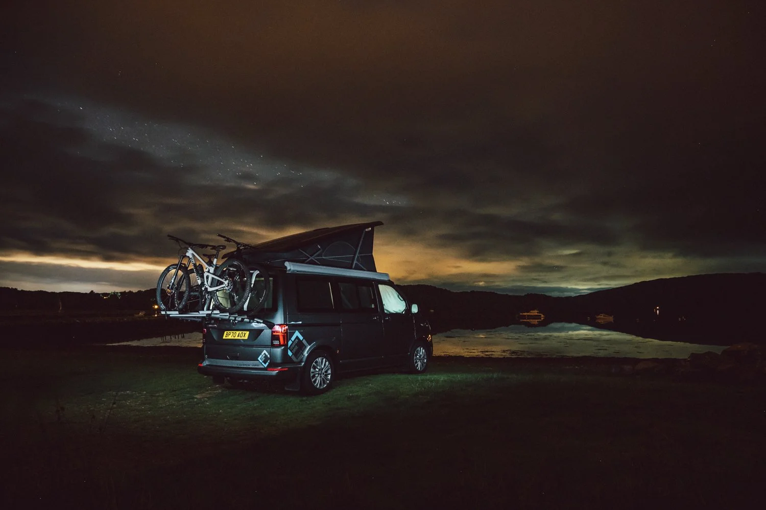 Leighton vans VW T6.1 california rental campervan. parked up for the night with the pop top up. overlooking a scottish loch.