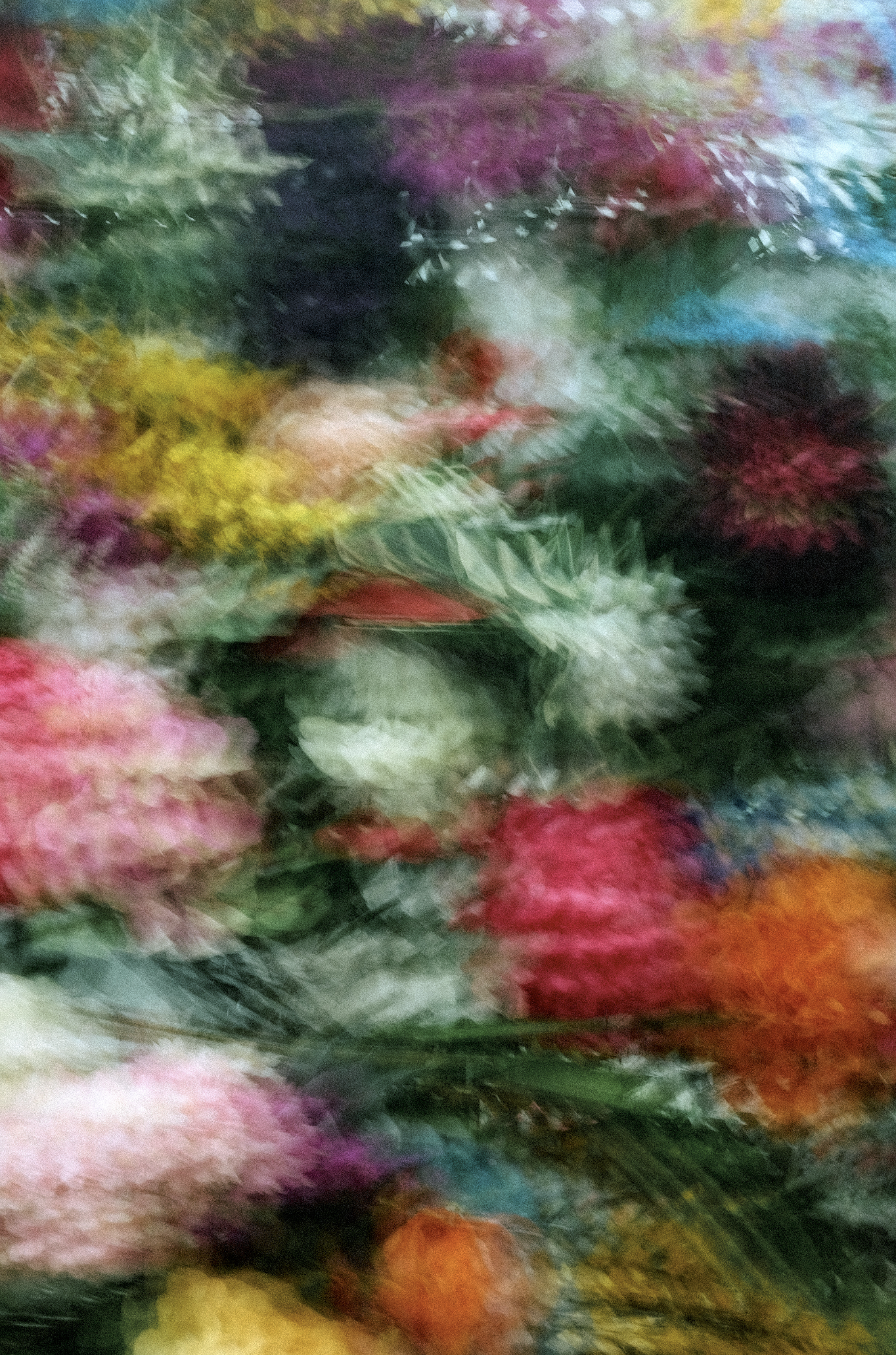 Blurred colorful floral arrangement with various flowers and greenery.