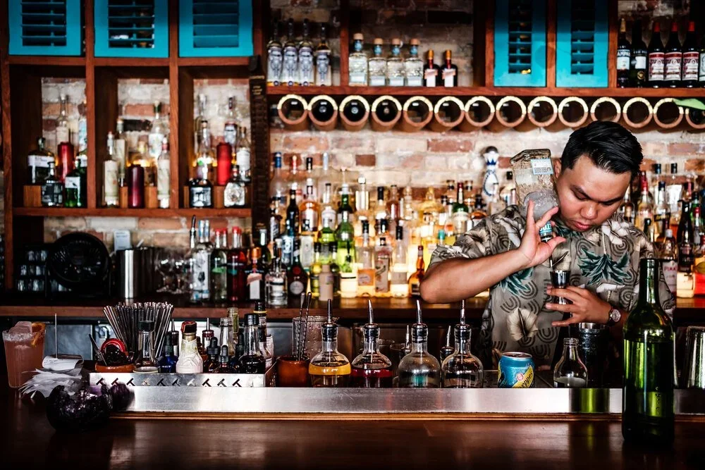 man working behind the bar mixing and pouring cocktails