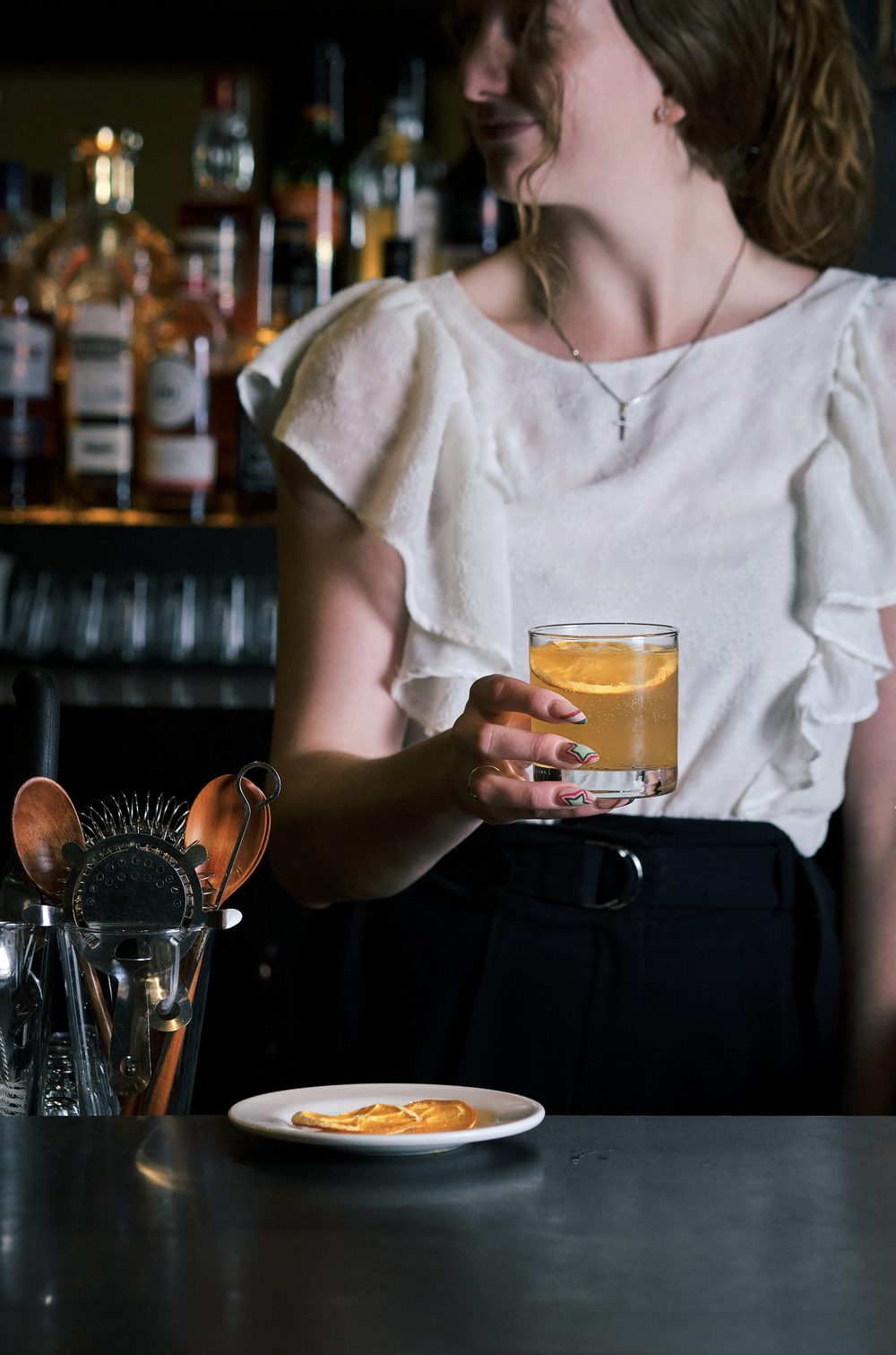 woman holding a cocktail behind a bar