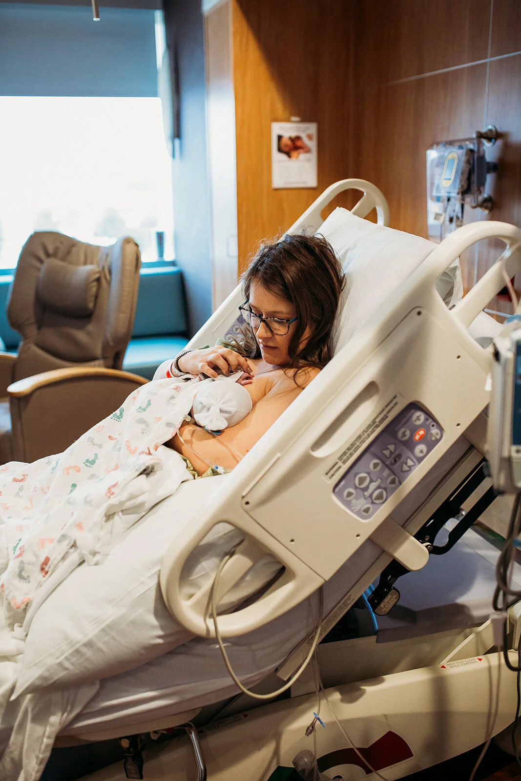 a mother in a hospital bed looking down at ther nursing newborn | Birth photographer at Medical Center Hospital in Odessa Texas