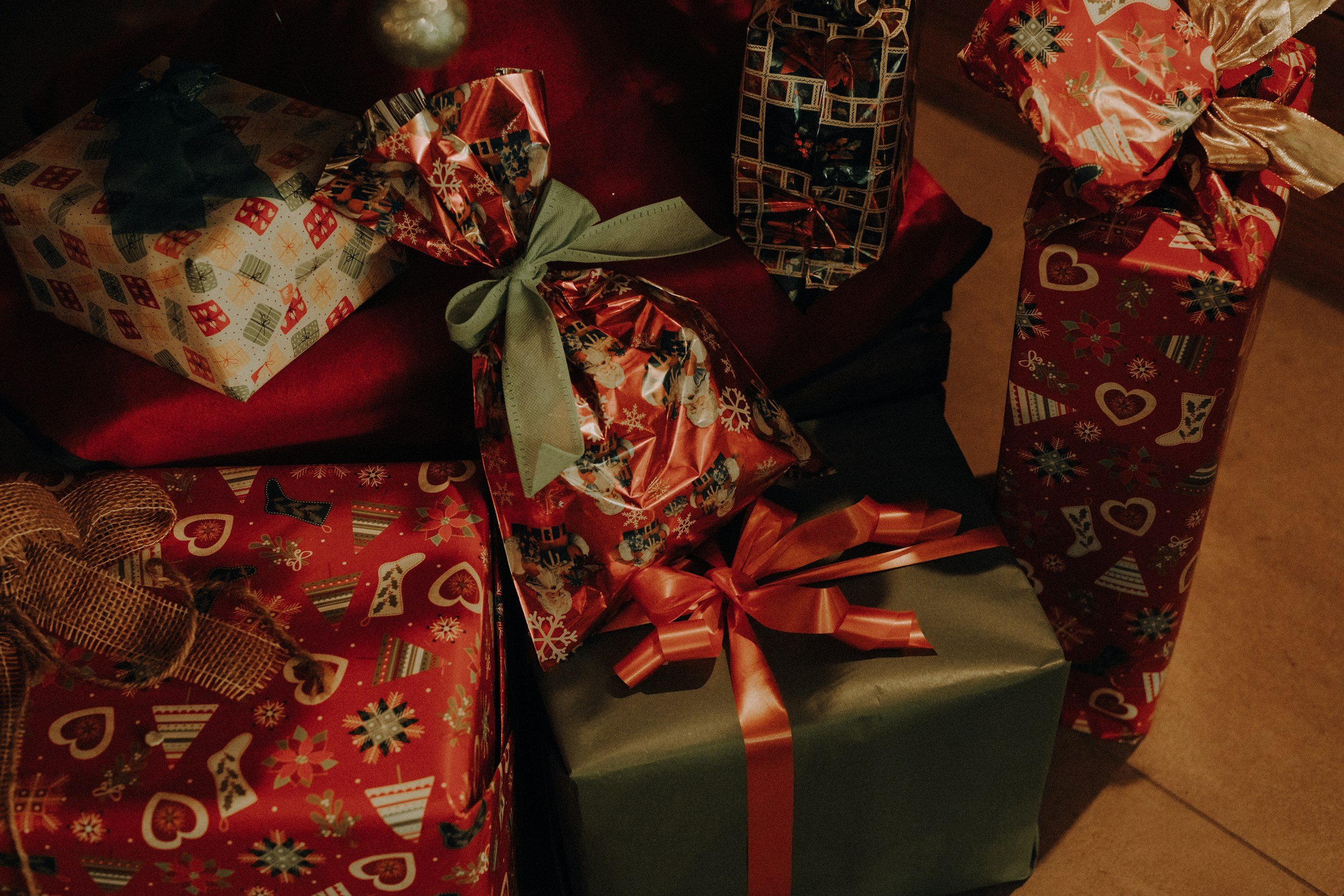 red and green christmas presents with bows sit on a floor