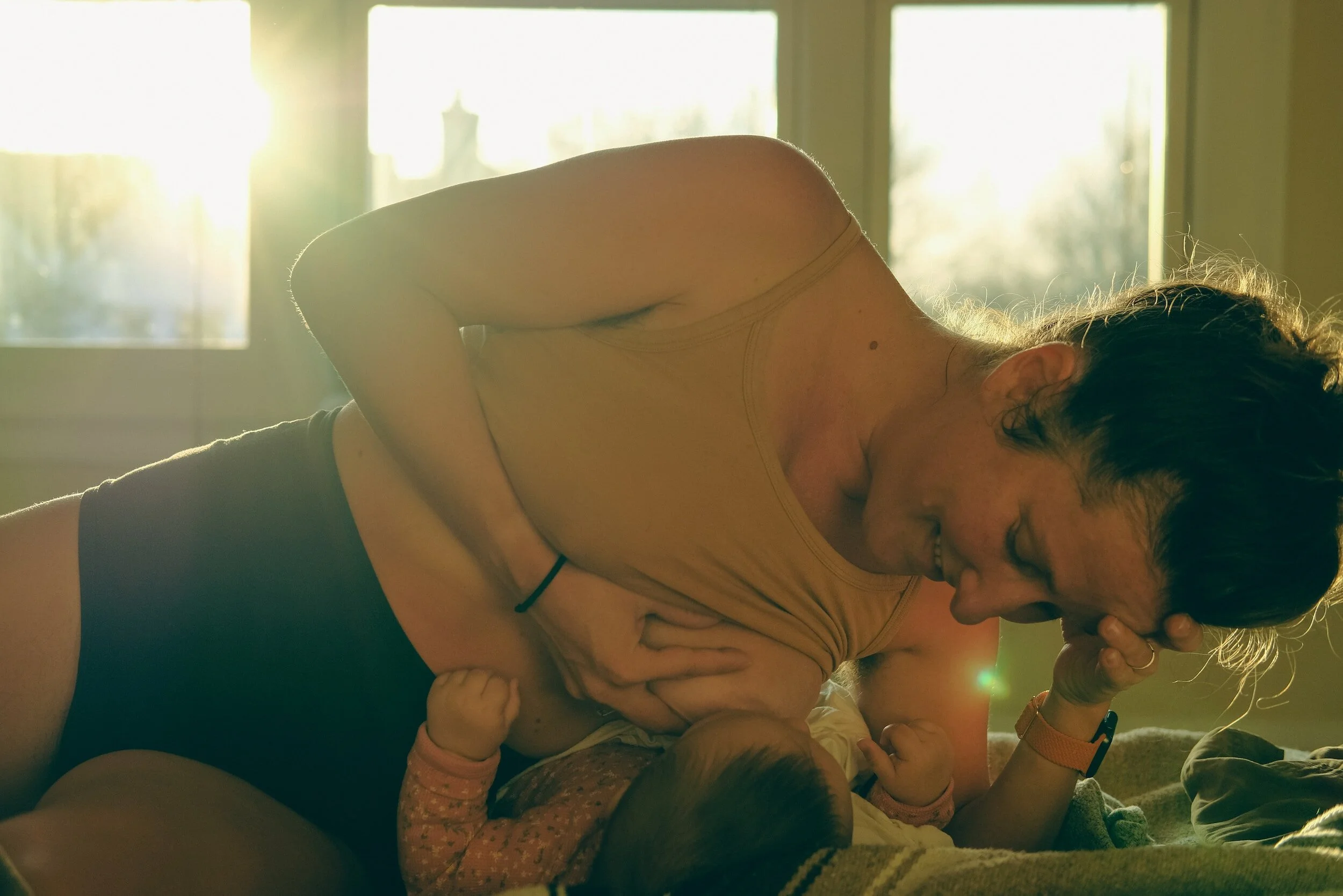 A person leaning over their baby nursing them.