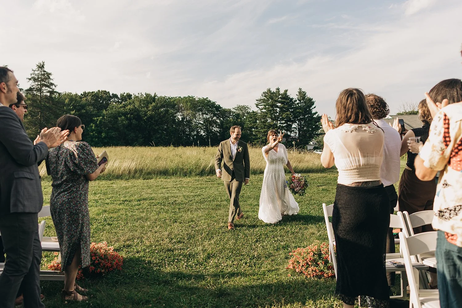 A bride and groom walk together down the aisle during their wedding ceremony at the red barn at hampshire college in amherst, massachusetts