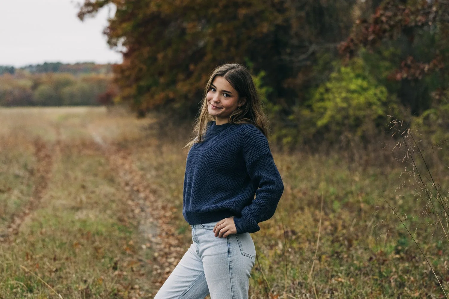 A northampton high school senior stands in a field for her senior portrait session.